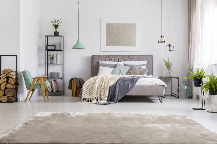 Modern bedroom interior with grey, king-size bed, metal shelf and fur carpet. 