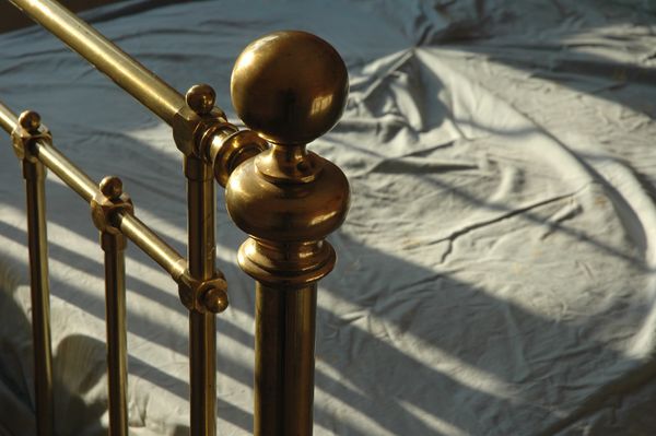 A close up of a brass bed frame 