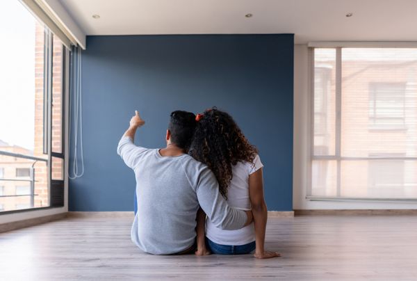 A couple facing a blue wall in an empty living room 