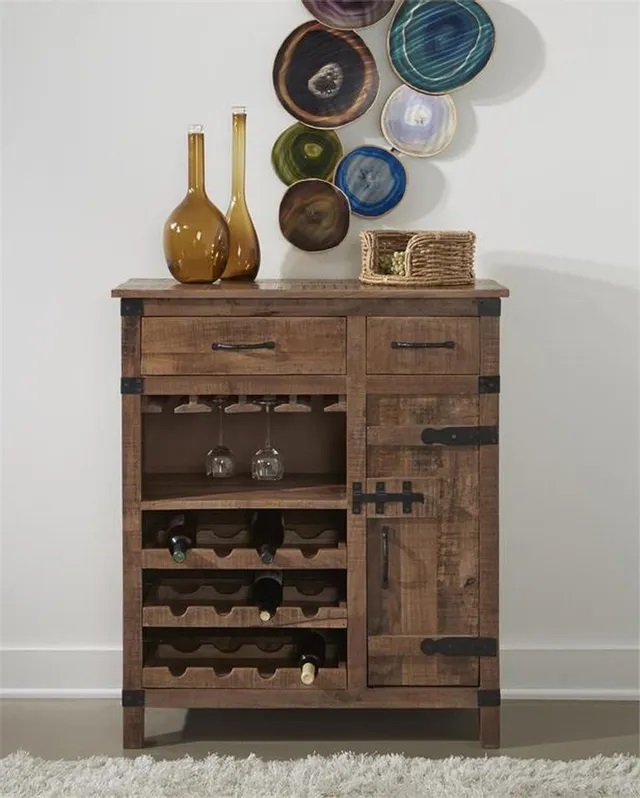 Photo of a darker wooden wine cabinet with two storage drawers and a pull out door with vases sittng on top and artwork on the wall behind it. 
