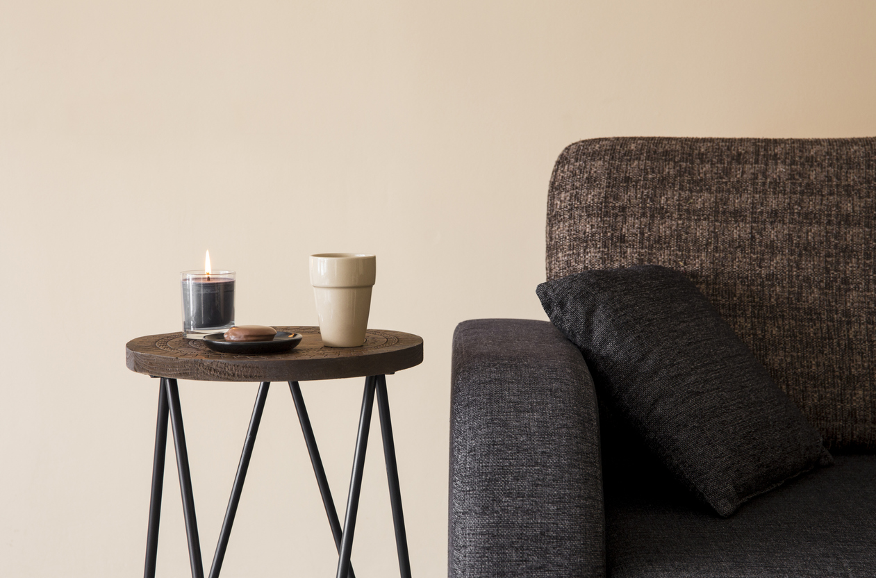 a minimalist brown side table with a cup and candle on it