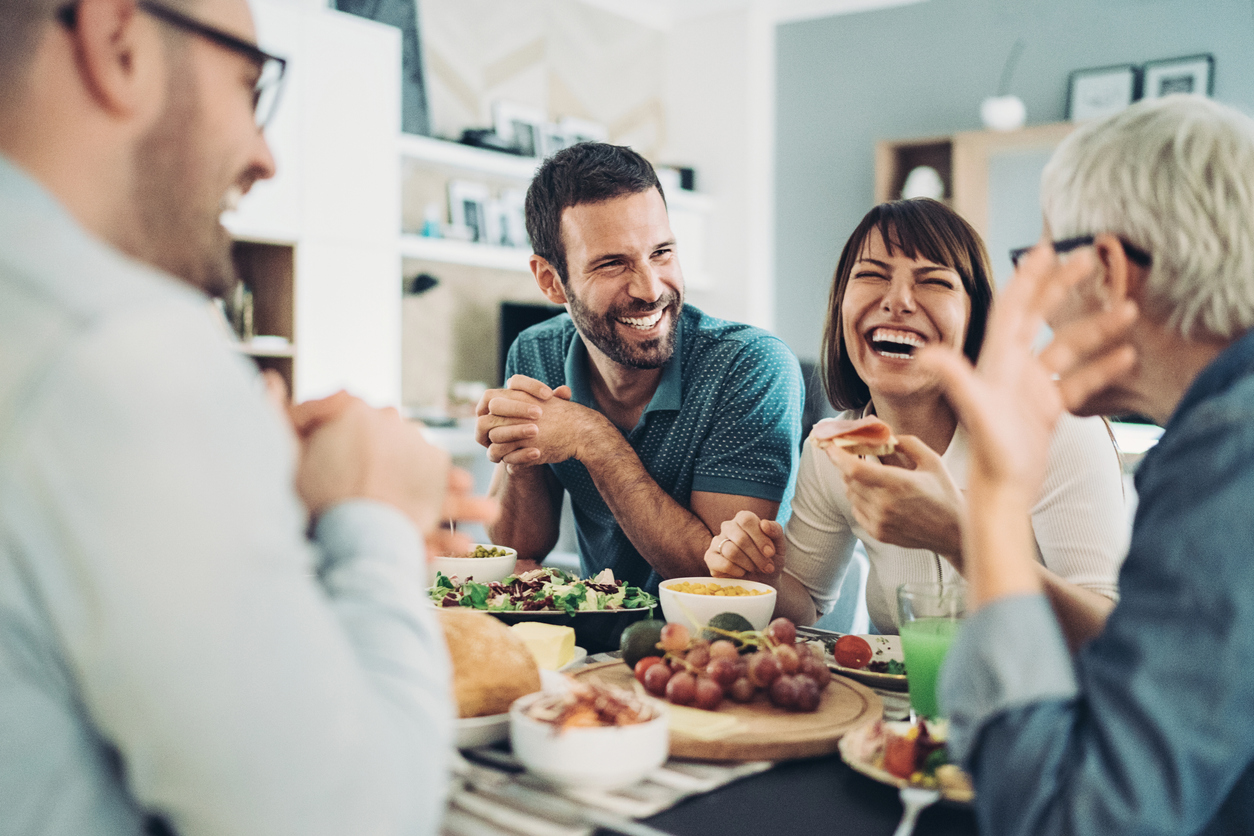 friends gathered around the table with food and drinks, having good time together