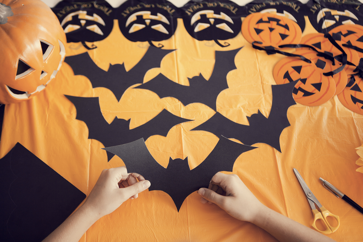 paper bats being cut out for indoor Halloween decorations