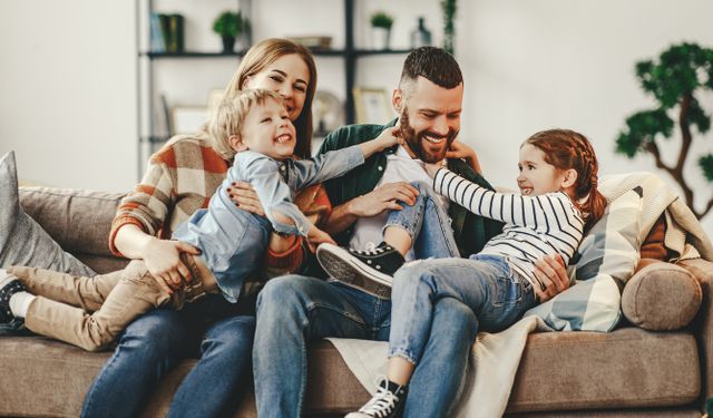 happy mother, father, and kids at home on the couch