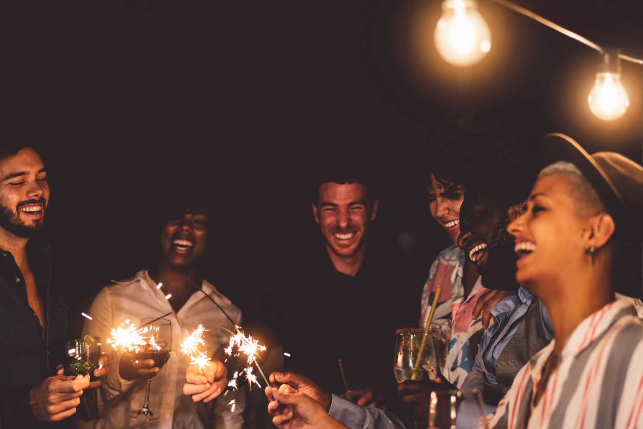 young friends celebrating new year eve with sparklers on patio