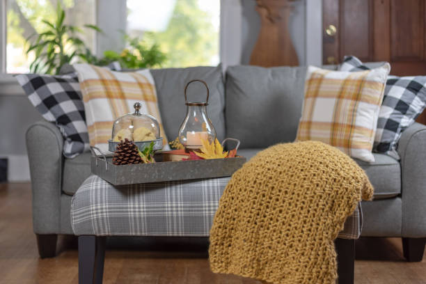 couch with plaid pillows with a knit blanket and seasonal decorations on ottoman