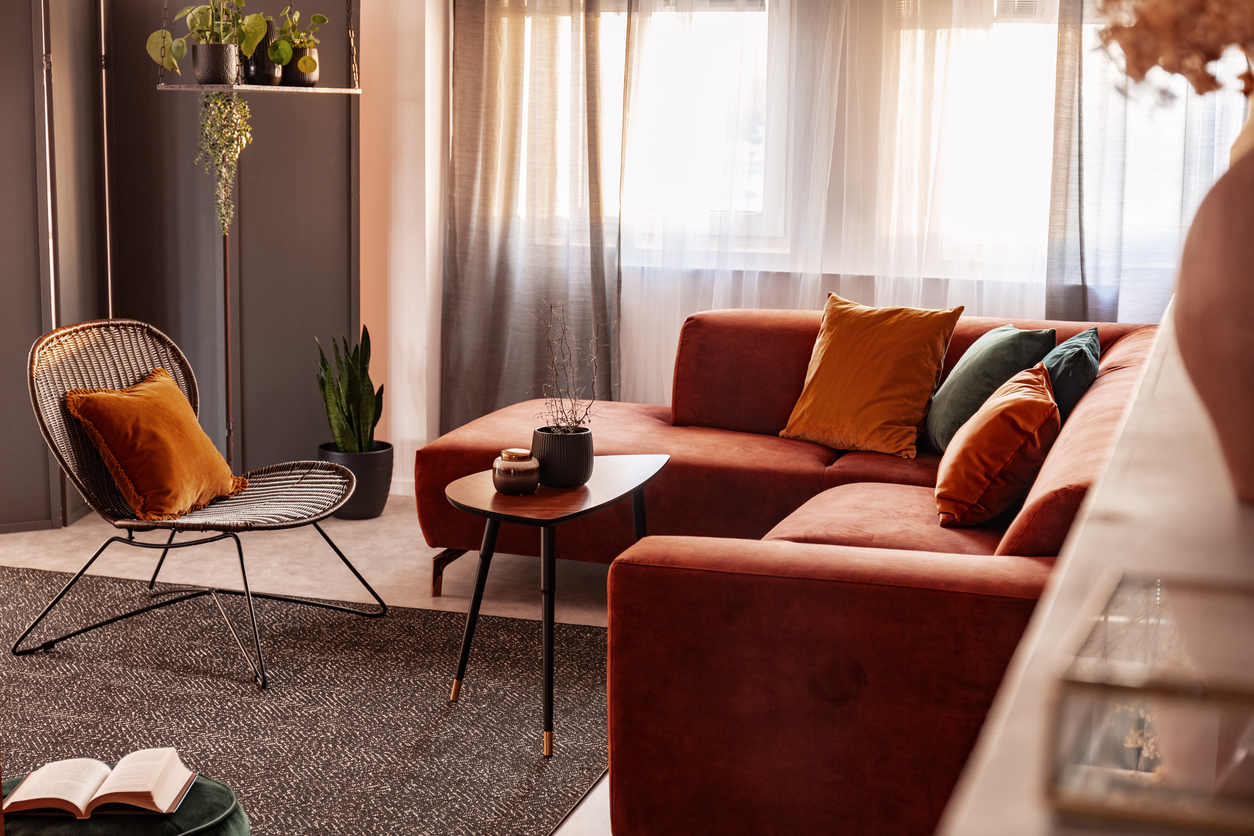 small coffee table in front of comfortable corner sofa in autumn colored living room interior