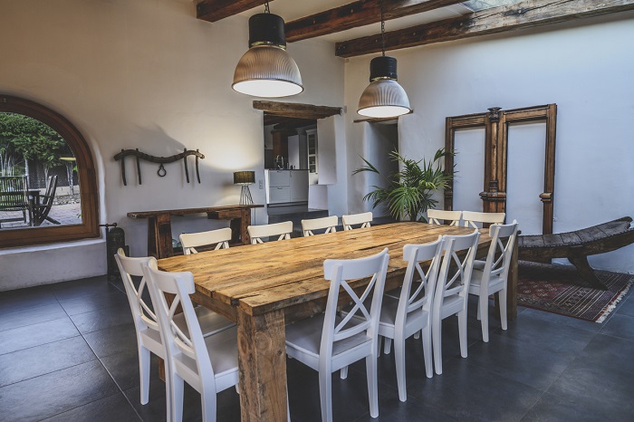Wide angle view of dining area with large wooden table and chairs.