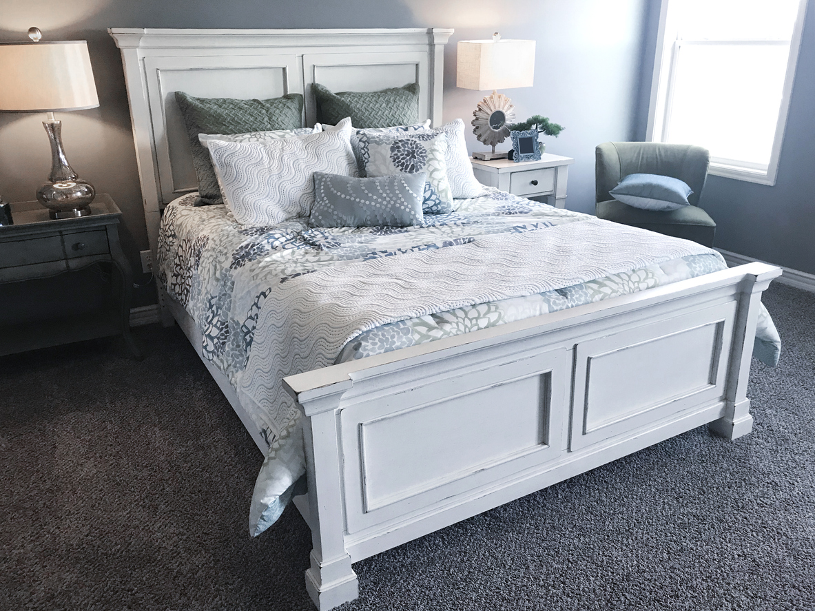 Farmhouse style white bedframe with pillows and a light, colorful bedspread