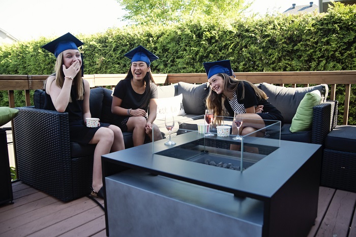 Women who have graduated highschool celebrating their graduation on outdoor furnishings