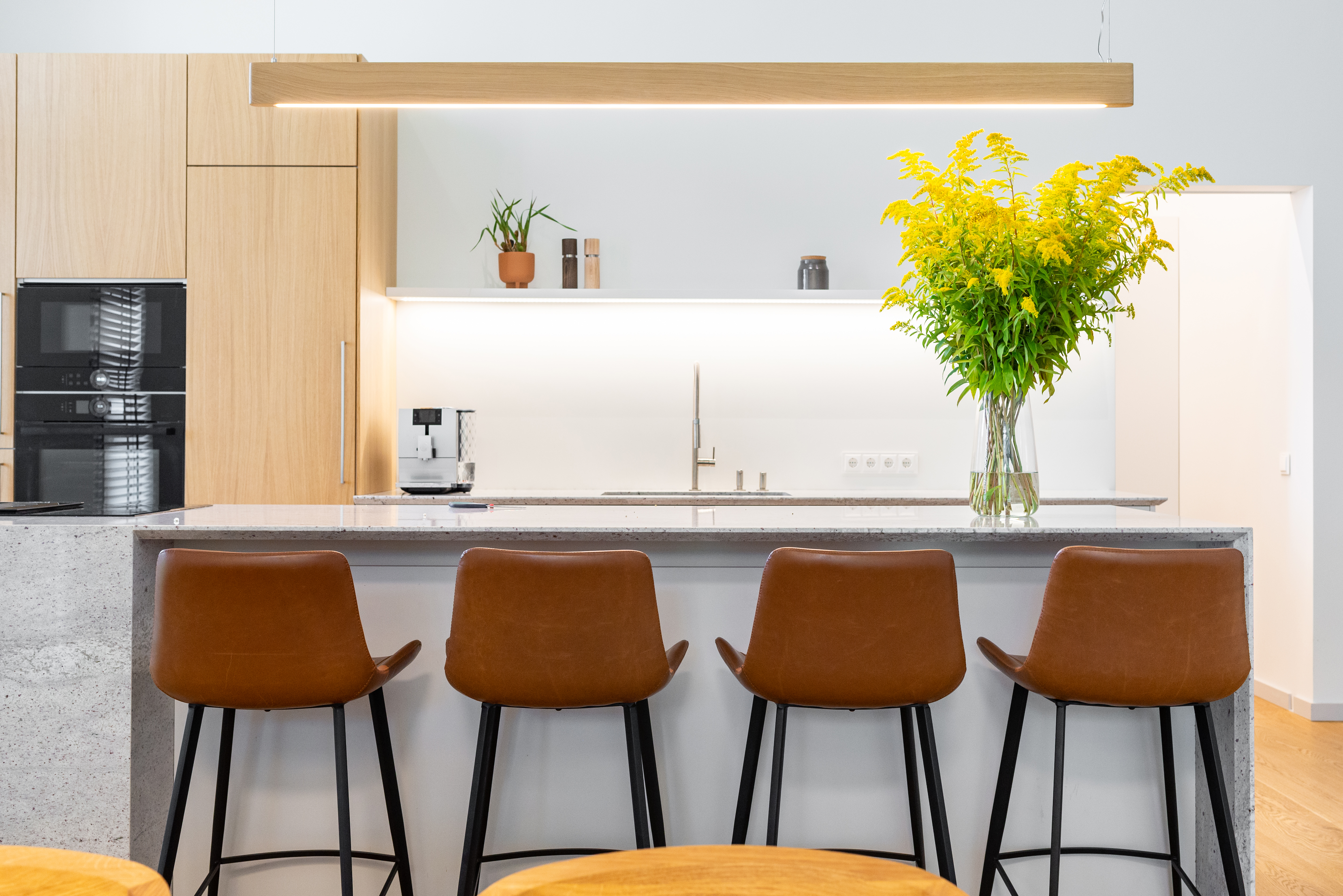 Four brown leather bar stools with backs at a kitchen counter