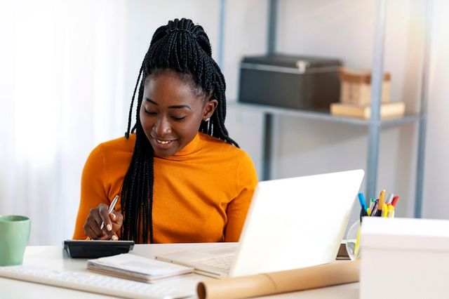 woman sitting in front of a laptop with a calculator