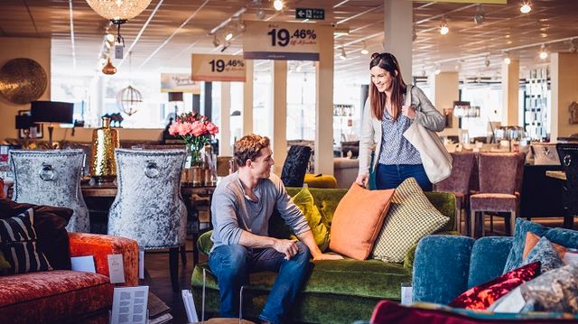 front view of a man sitting on a couch in a furniture store 