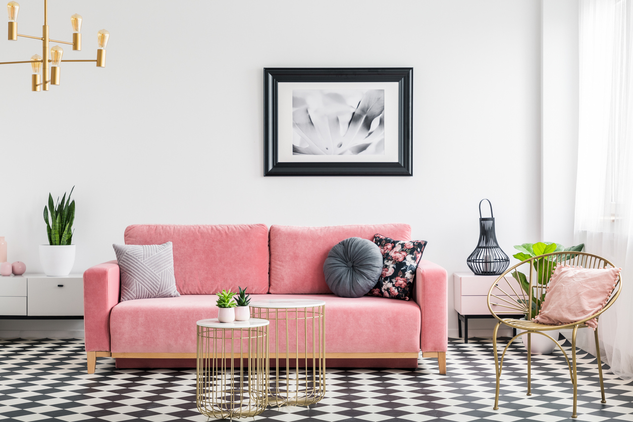 Gold finished furniture with a pink couch and wall art