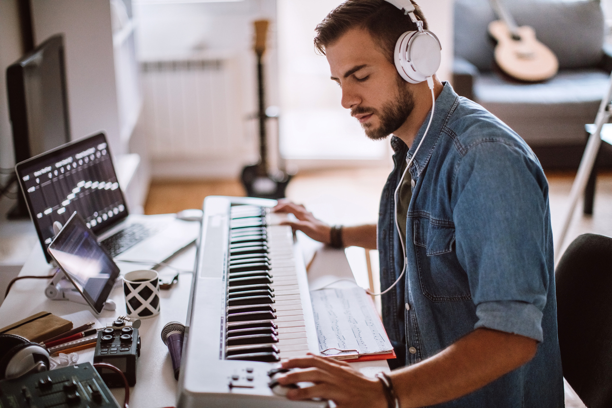 man recording music at a keyboard in a bedroom