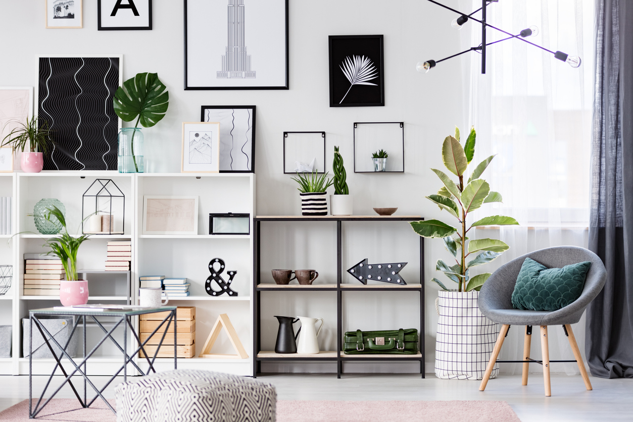 lamp above grey armchair with green pillow in bright living room interior with table and ficus