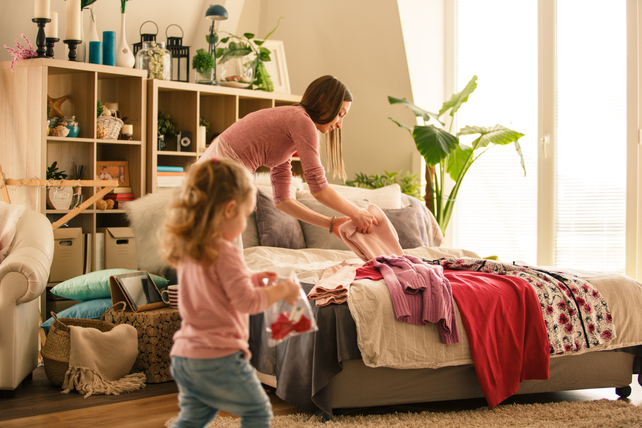 mother and her little baby girl folding clothes in their bedroom