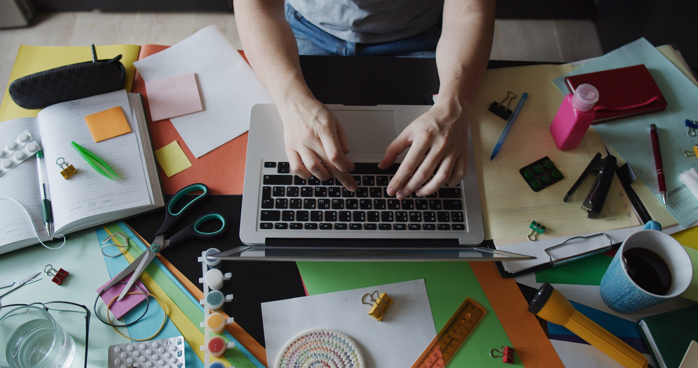hands of person doing office work at cluttered table 