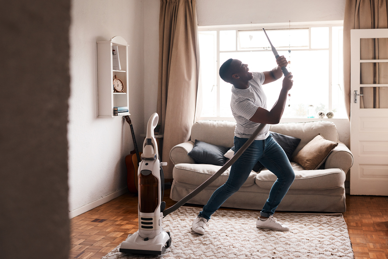 young man dances while he vacuums his living room