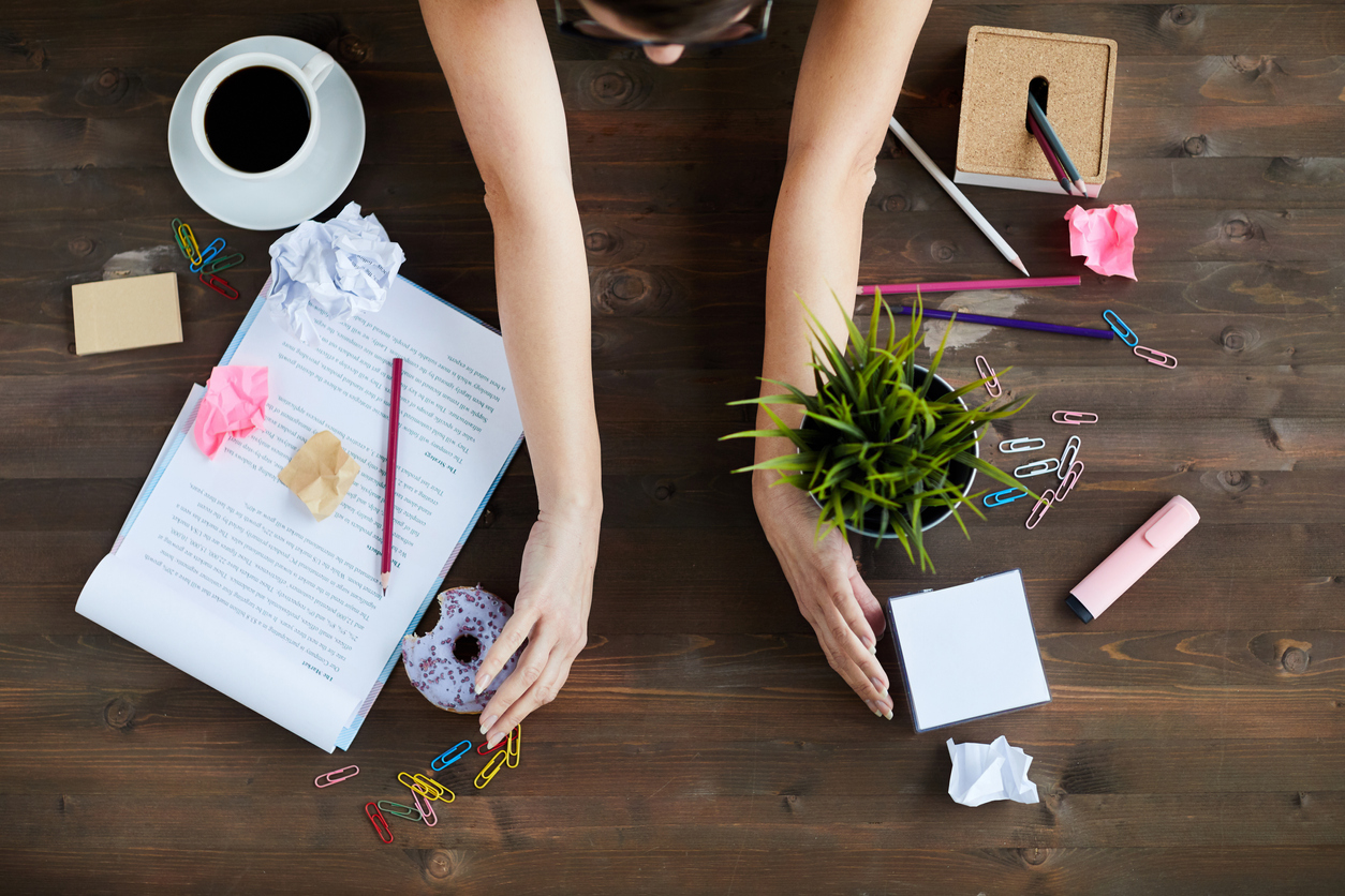 overhead view of woman sorting out mess on home office desk