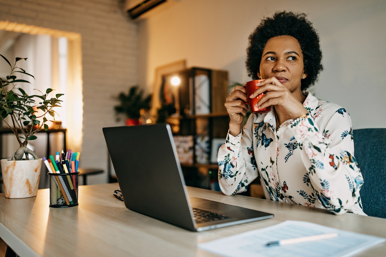 woman drinks from mug while sitting in her organized home office