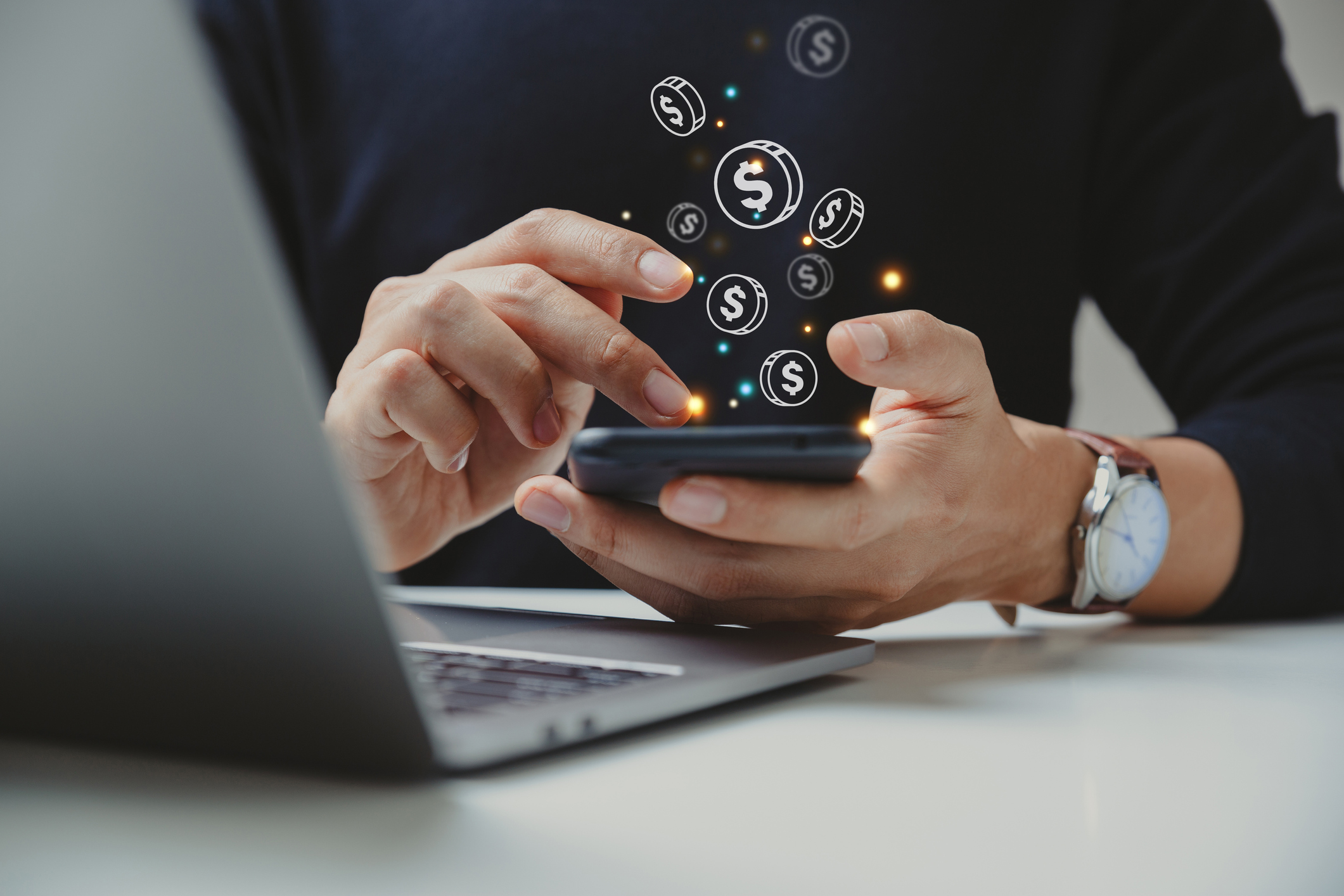 A person using a calculator while graphic coins float against a black sweater 