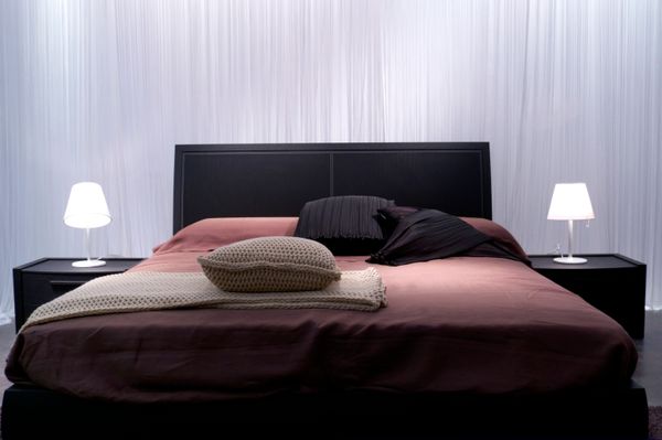 A black bed frame with bedding and lighting 