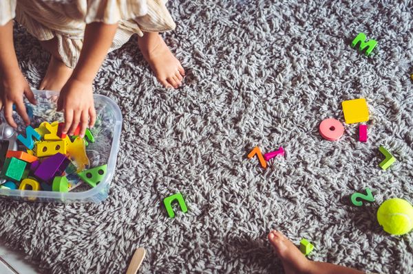 A child playing with block on gray carpeting 