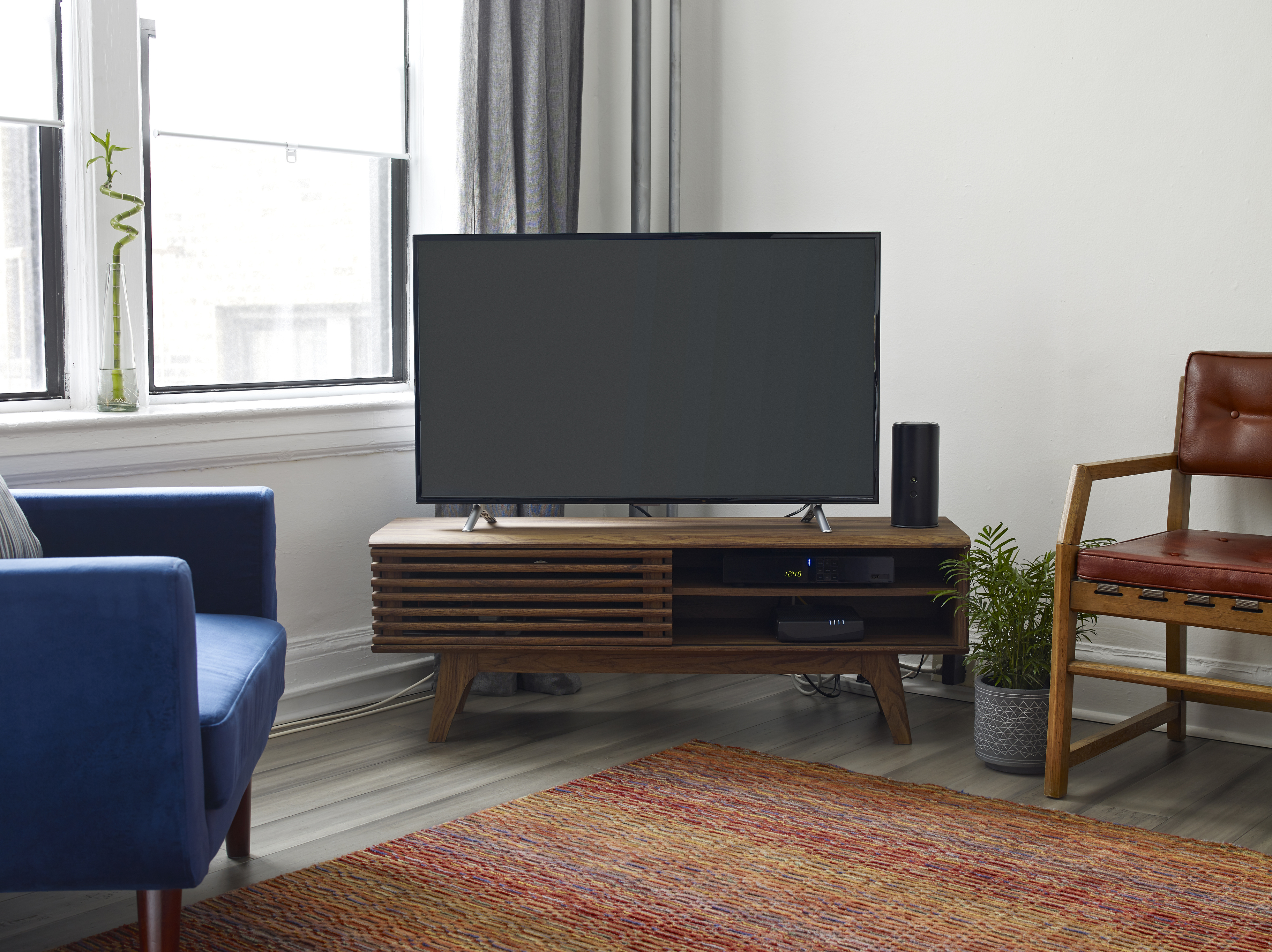 A wooden corner TV stand with a TV on it