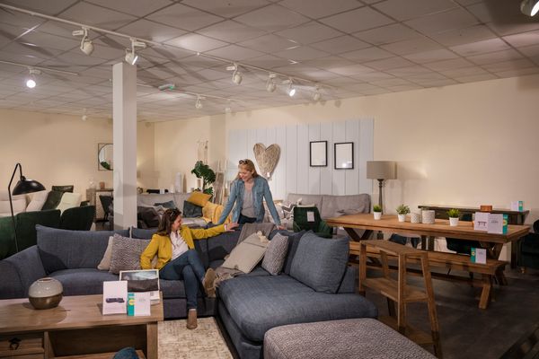 Two women trying out a sofa in a store 