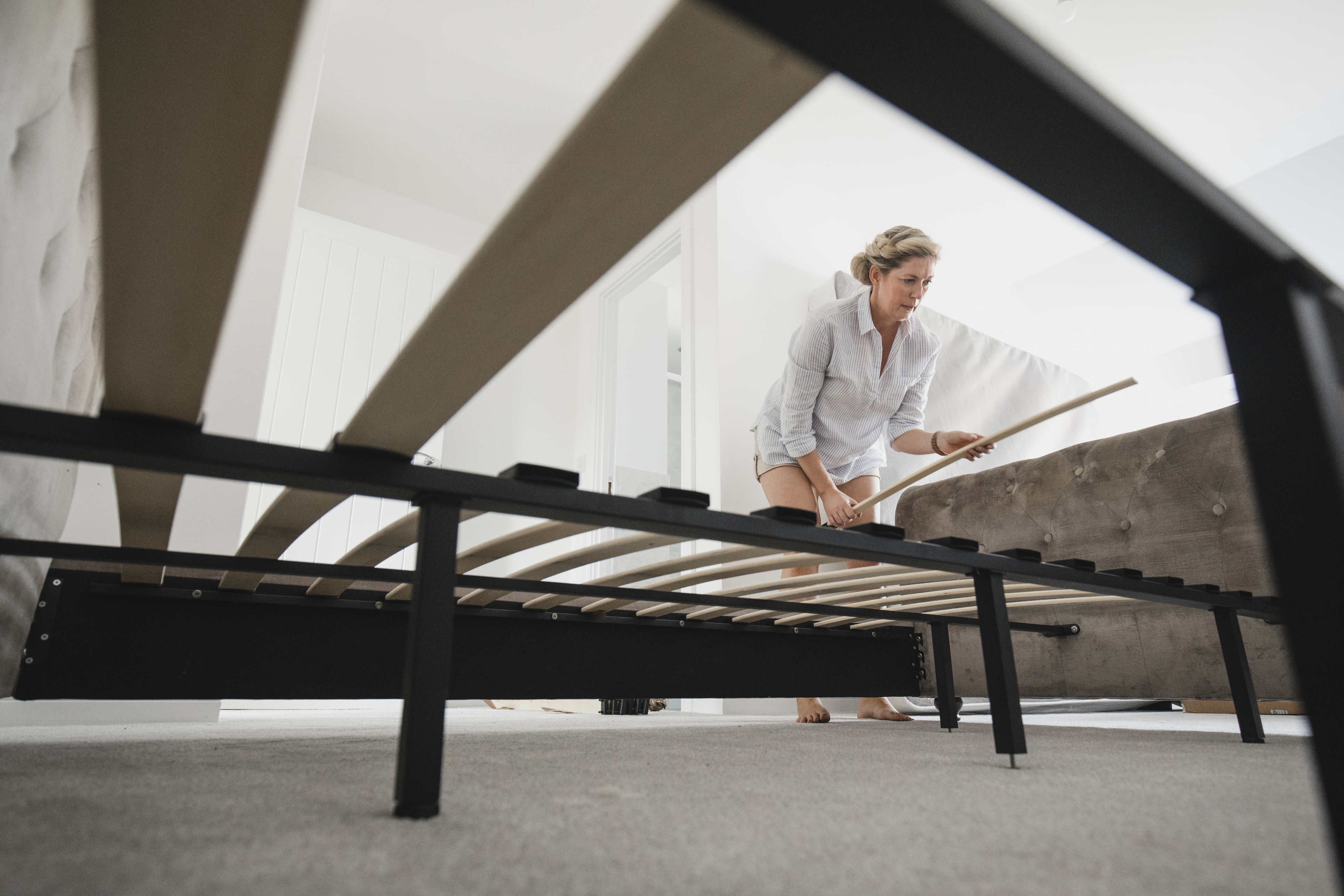A ground-up view of a woman putting together bed frame with slates 