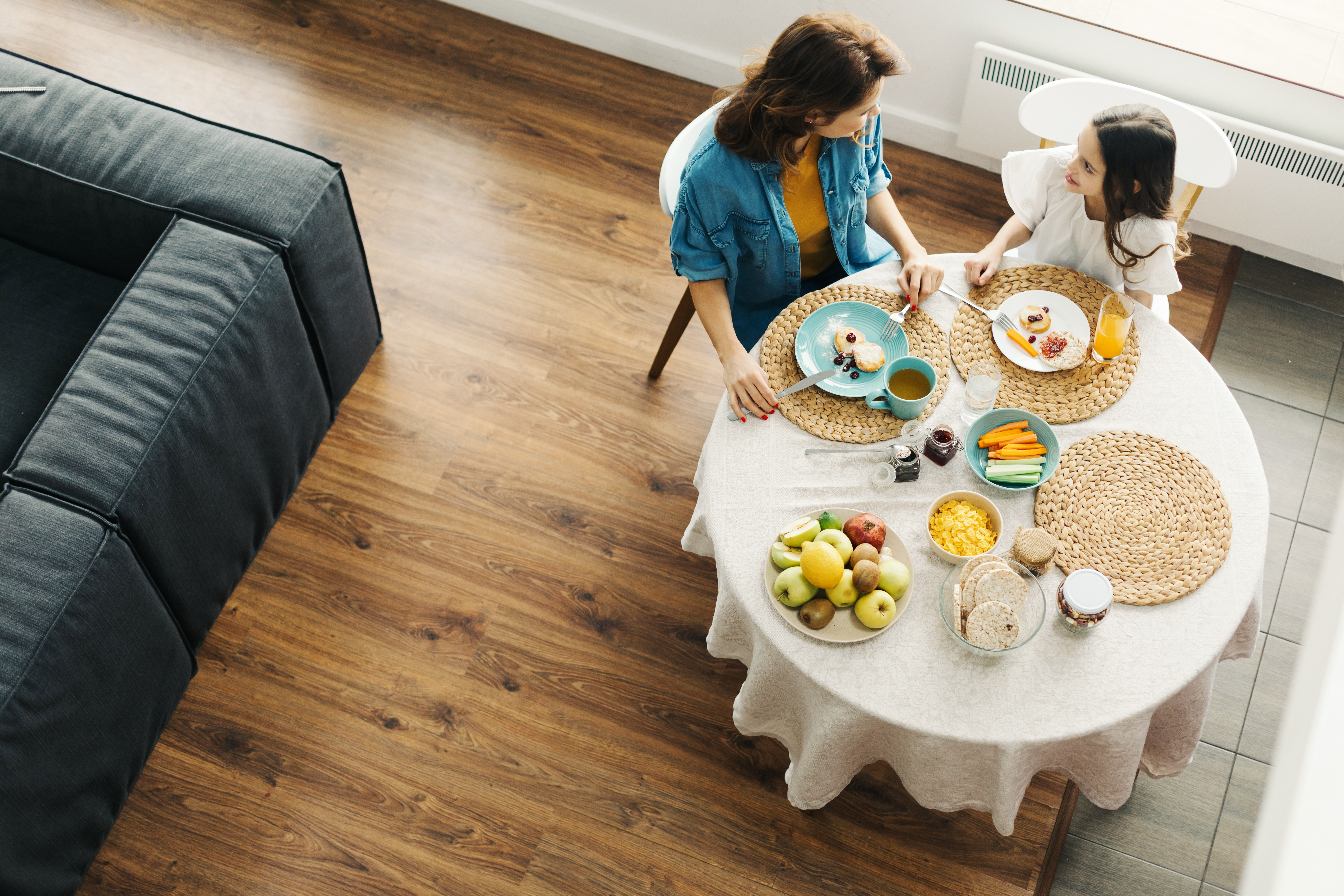 A mother and daughter eating around a round table with jute plate settings