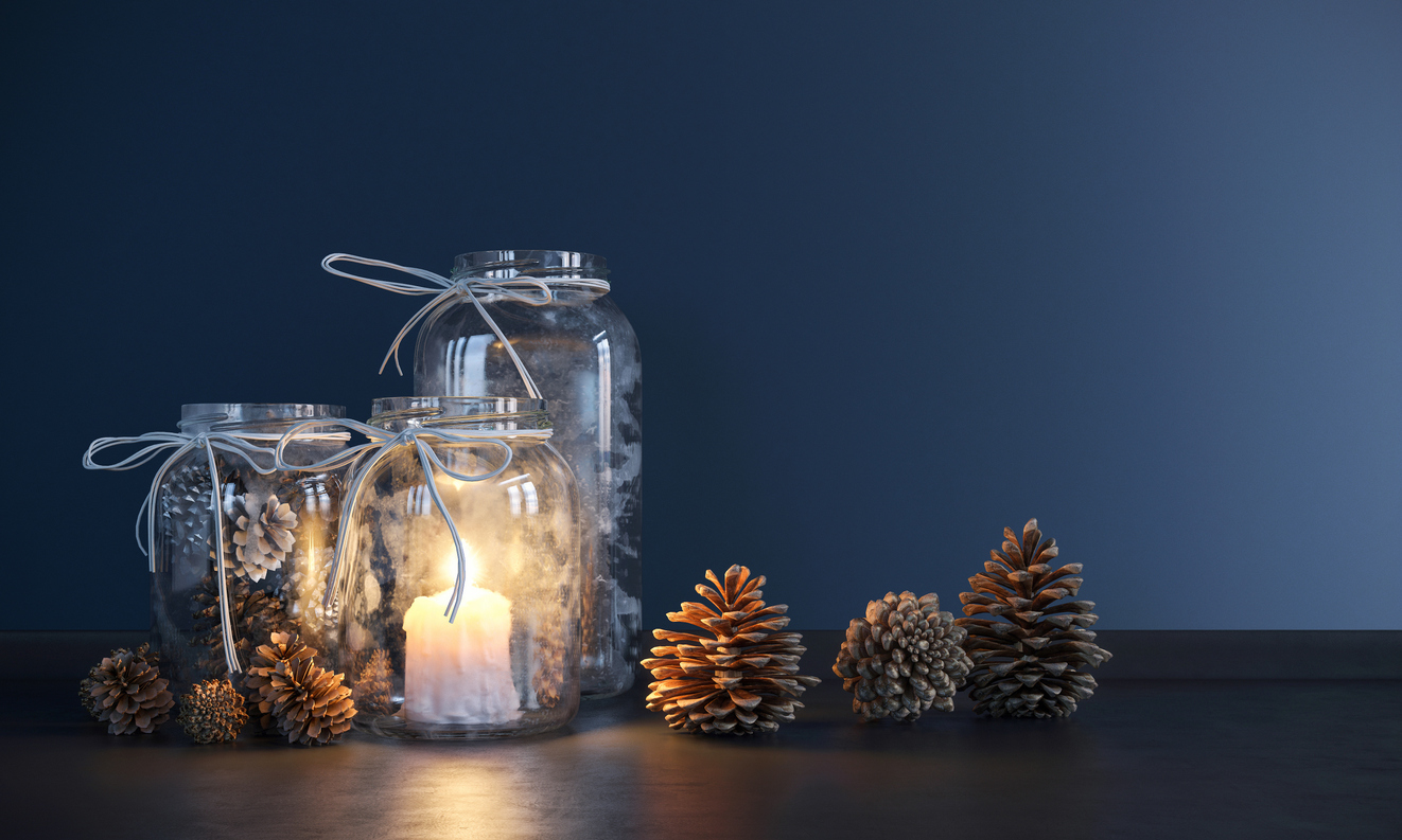 mason jars with lit candles in a dark tablesetting and surrounded by decorative pinecones