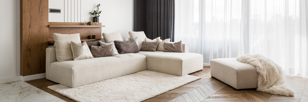 a cozy sectional with many throw pillows and an ottoman with a blanket draped over it