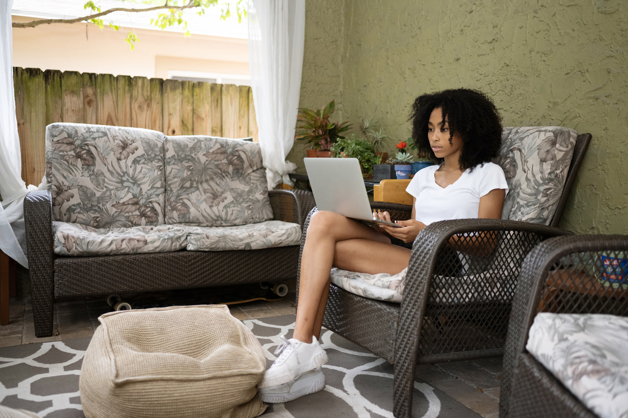 teenage girl using a laptop computer outdoors on the porch at home