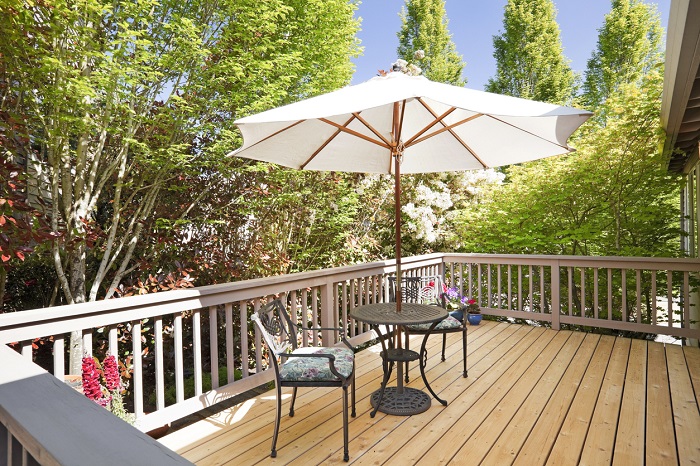Sunny back deck with table, chairs, and umbrella.