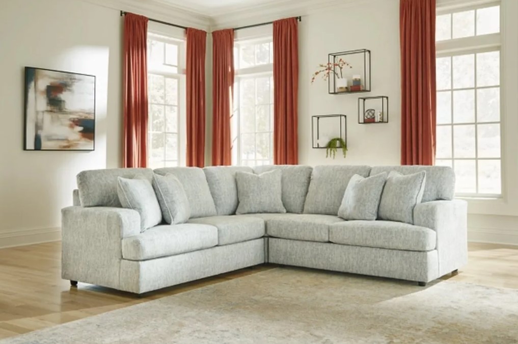 Stylish light grey sectional sofa in a living room with red curtains