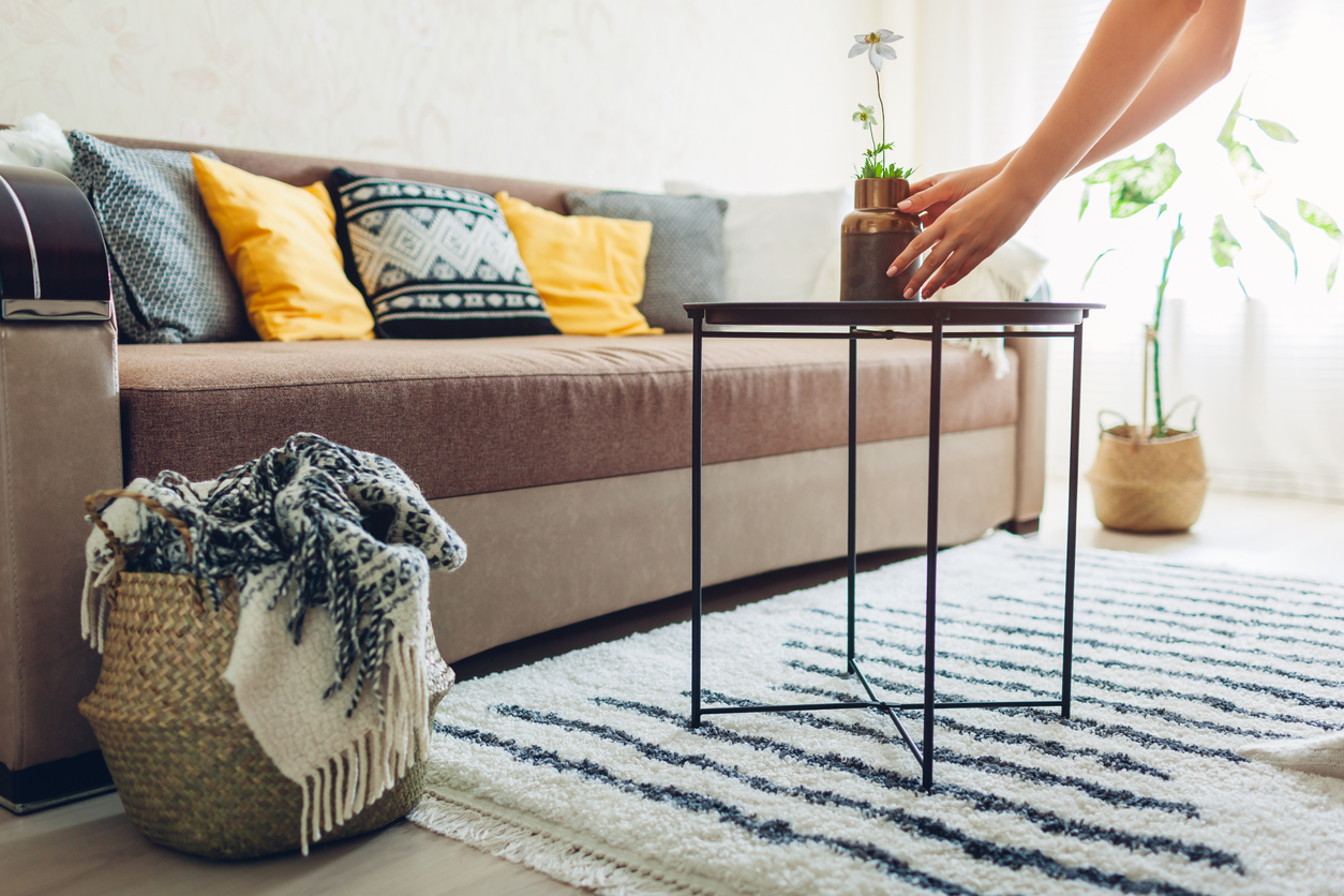 person arranging flowers in a vase in boho chic style living room. 