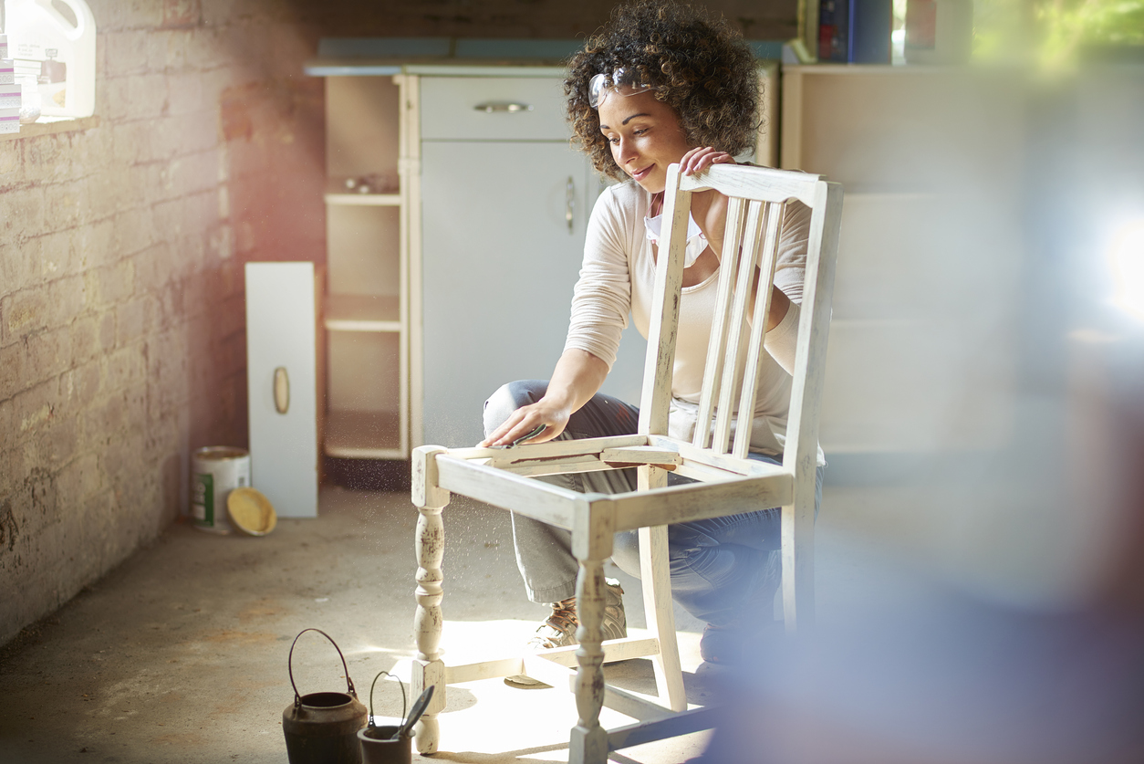 woman restores and improves an old wooden chair in her workshop