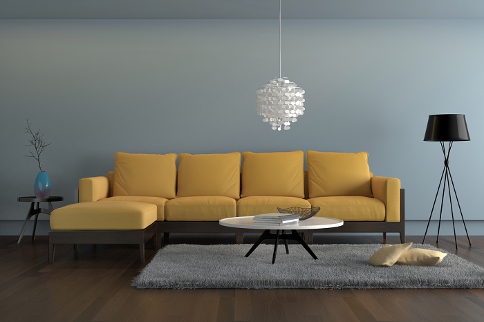 Living room showing a yellow sofa, with a lamp, ornate pendant and a table with decoration.