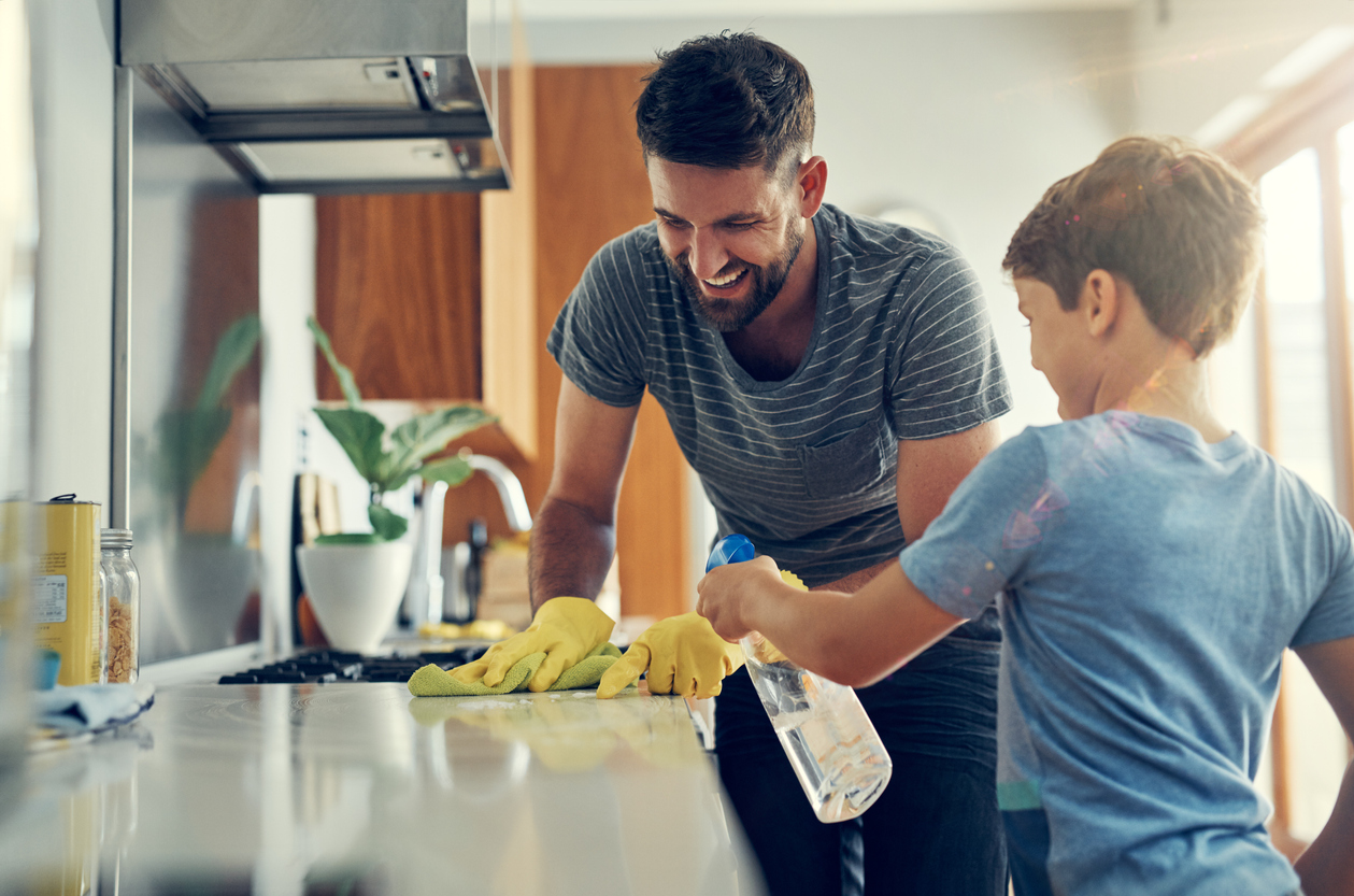 a dad and son clean the countertops in the kitchen