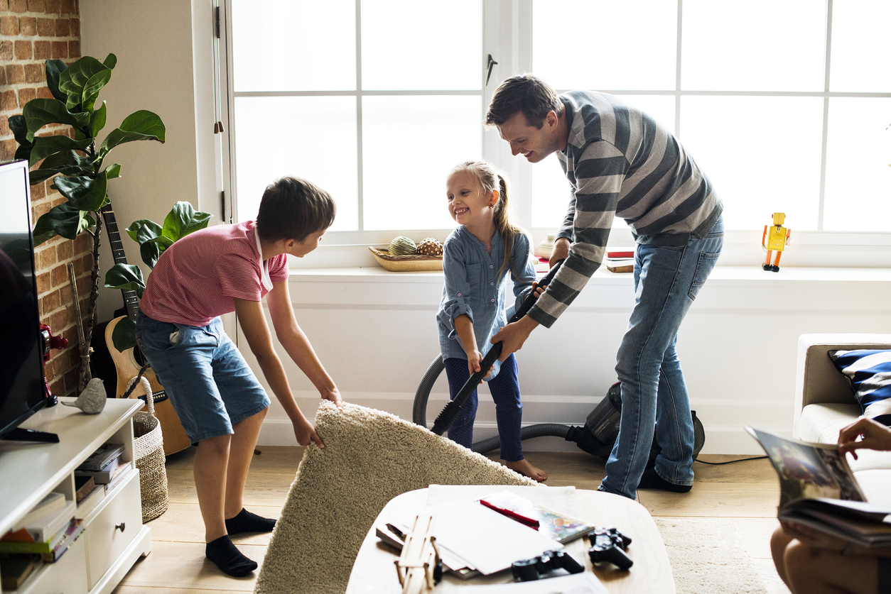 Dad and two kids vacuum the living room