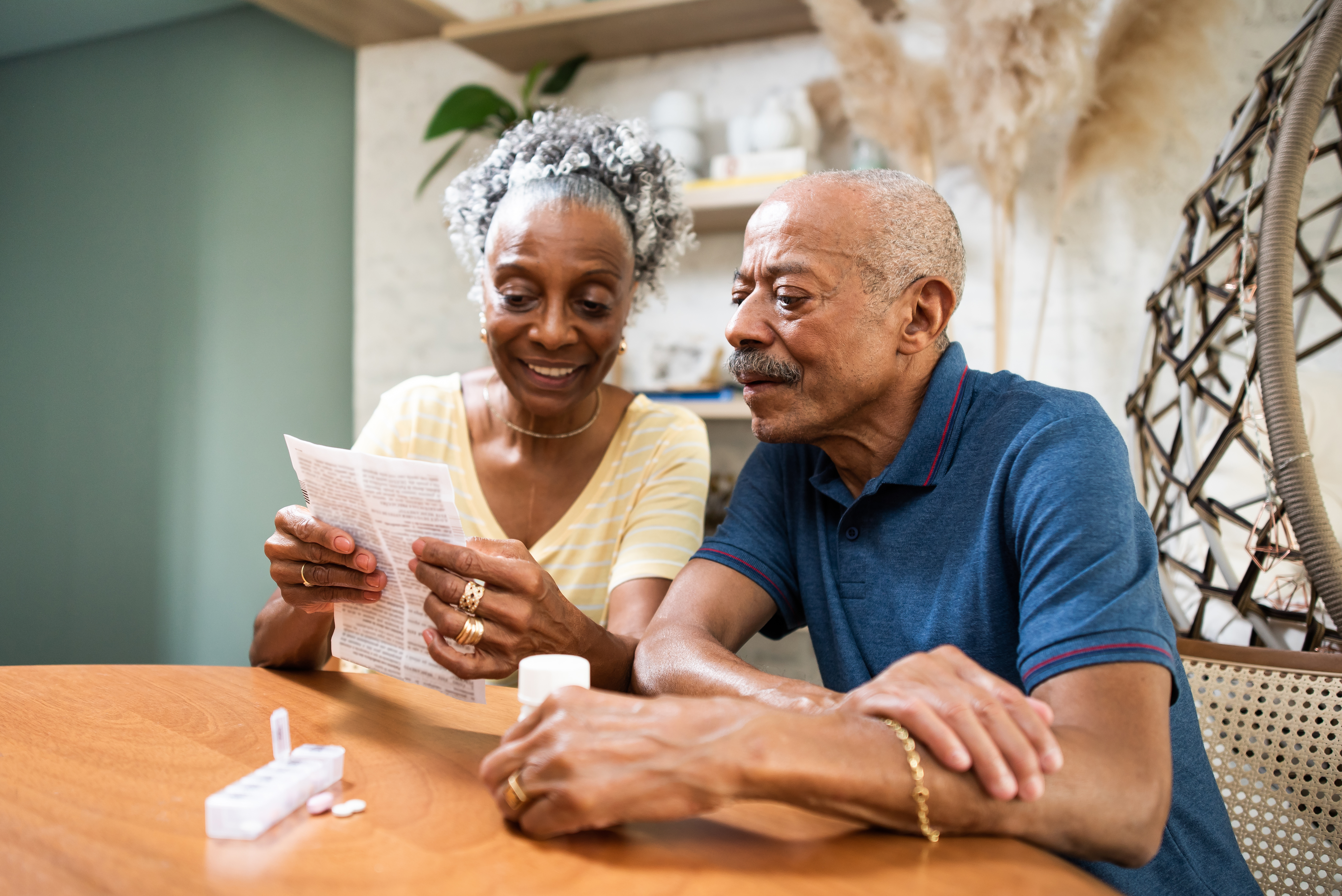 An elderly couple smiling as they read a paper 