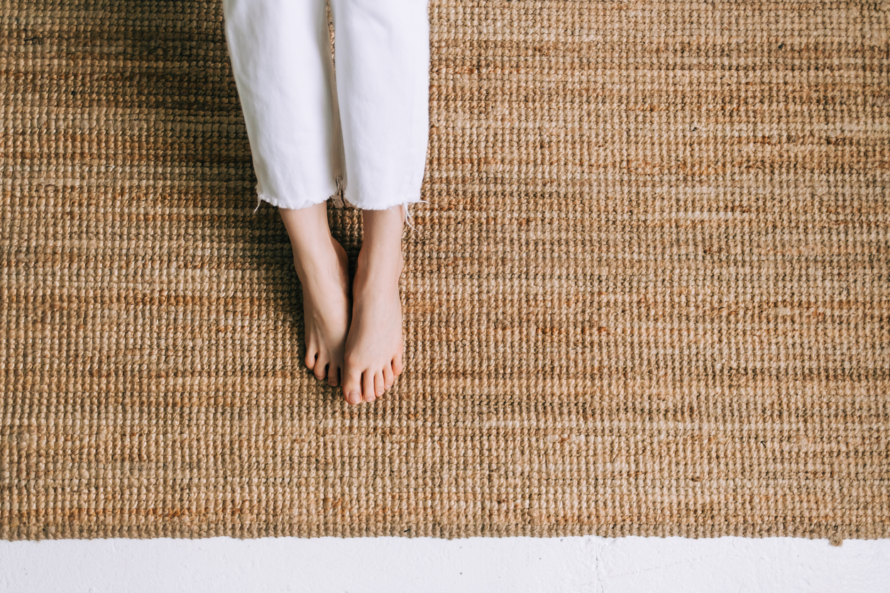 woman in white capris rests bare feet on jute rug