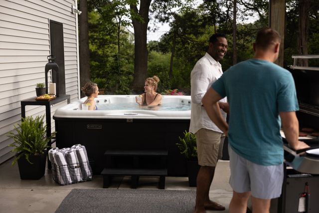 Front view of two men grilling and two women chatting in a Nordic hot tub