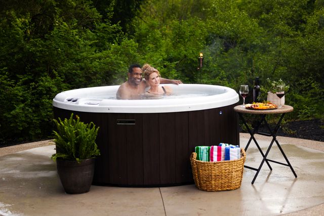 front view of a couple sitting and smiling posing for a picture in a round hot tub
