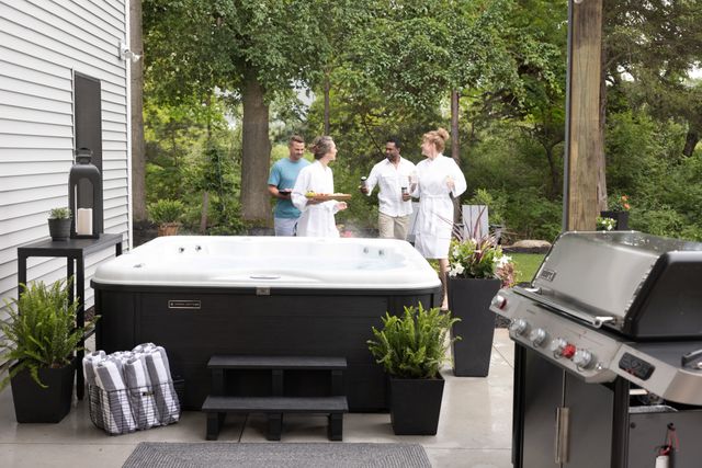 front view of a group of four people walking with food and drinks towards a hot tub
