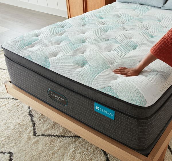 A hand tests the surface of a Beautyrest pillow top mattress