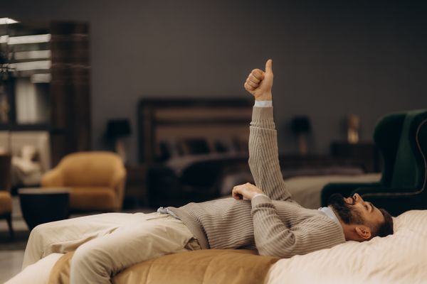 A man on a mattress with a thumbs up in the air 