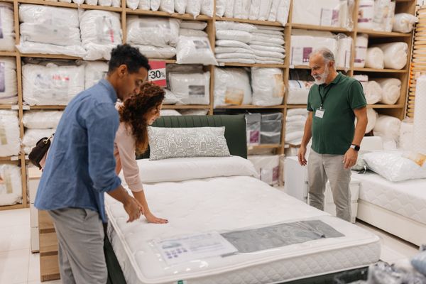 A couple pressing on a mattress in a store 